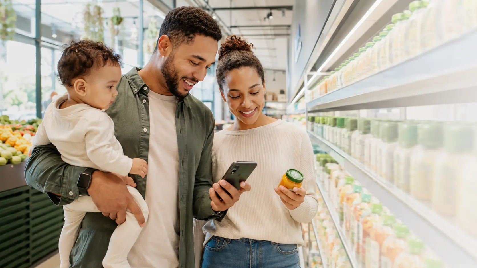 Parents with their baby checking food information on a smartphone in a supermarket